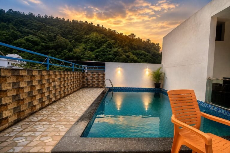 Rooftop pool with loungers and hill view at sunset at Hotel Kedar Inn by Around Stays