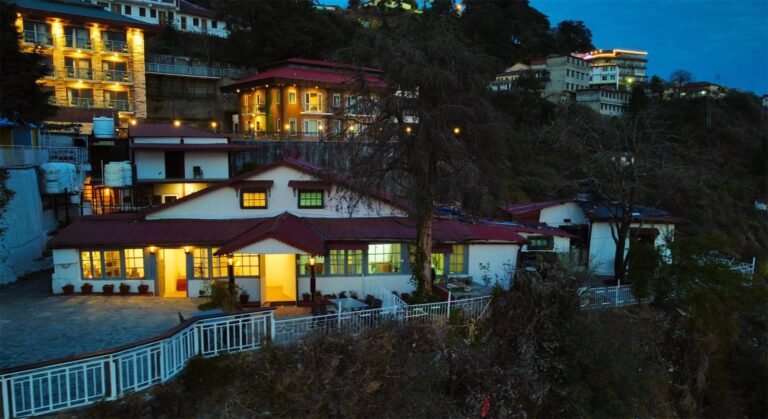 Hillside hotel building lit up at dusk at Oslo Mussoorie by Around Stays