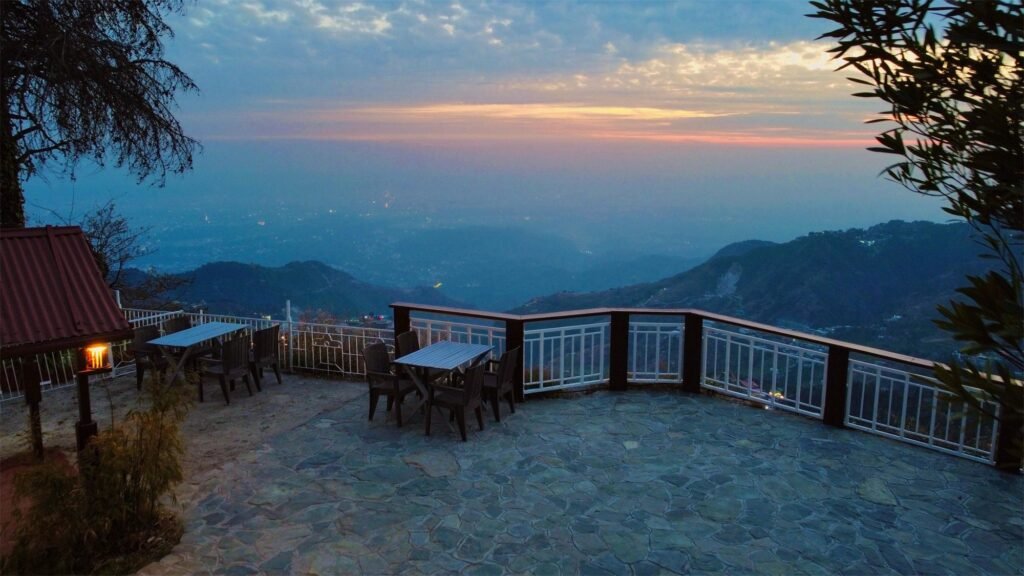 Open terrace at sunset over the valley at Oslo Mussoorie by Around Stays