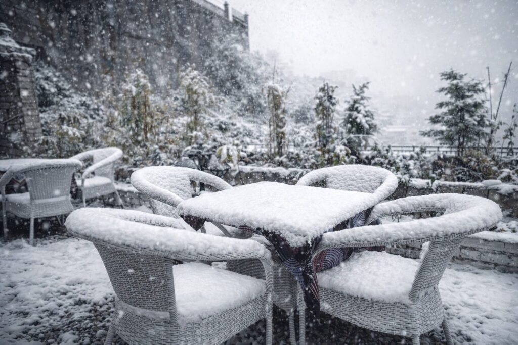 Snow-covered terrace seating in winter at Oslo Mussoorie by Around Stays
